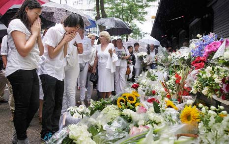 People react as they look at flowers placed in front of a marking the commemoration of the victims of Malaysia plane rash in Rotterdam.