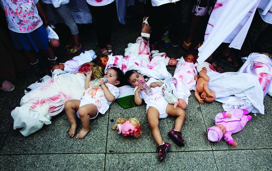 Two babies are placed between dolls covered with red paint during a demonstration, most of them women and children, against Israel's military offensive in Gaza in Berlin, Germany.