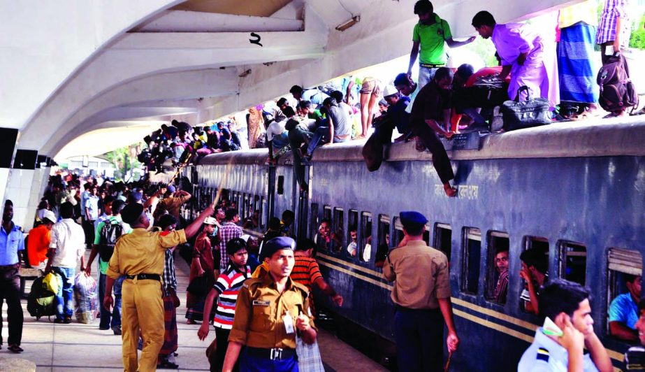 Railway security men bringing down passengers who managed to make room on the roof-top of train illegally at Kamalapur Station on Saturday.