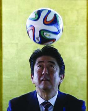 Japan's Prime Minister Shinzo Abe heads the ball during a meeting with Brazilian soccer players in Brasilia on Friday.