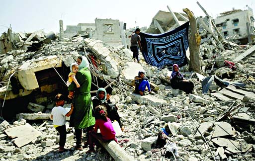 Homeless families stand atop the wreckage of a house which witnesses said was destroyed by an Israeli air strike in Rafah in the southern Gaza Strip on Saturday. Photo: Internet