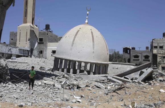 A Palestinian boy stands next to the remains of a mosque in Khuzaa town, which witnesses said was heavily hit by Israeli shelling and air strikes during Israeli offensive, in the east of Khan Younis in the southern Gaza Strip August 6, 2014.