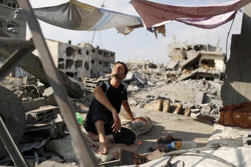 A man looks up as he sits in a tent amid the ruins of his home that he says was destroyed by Israeli air strikes in the Shejaia neighbourhood in Gaza City.