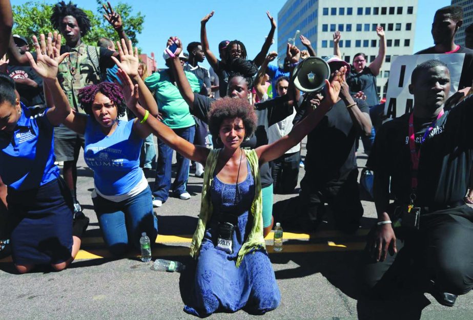 Protestors drop to their knees and put their arms in the air during a rally for Michael Brown Jr., who was shot and killed by a Ferguson police officer last Saturday on Tuesday.