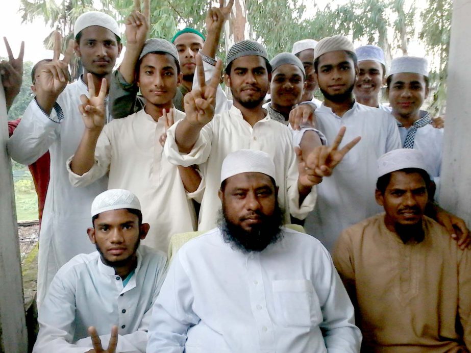 Students of Simrail DSNS Alim Madrasha are seen Wednesday with their Principal Maolana Farid Uddin celebrating success of record 100 per cent pass with GPA 5 in this year's Alim Examination under Madrasha Education Board. Chairman of the Madrasha Governi