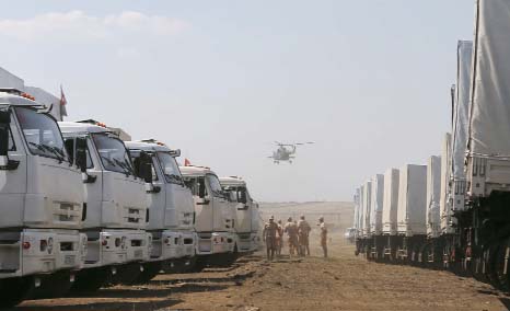 A military helicopter flies above a Russian convoy of trucks carrying humanitarian aid for Ukraine, parked at a camp near Kamensk-Shakhtinsky, Rostov Region.