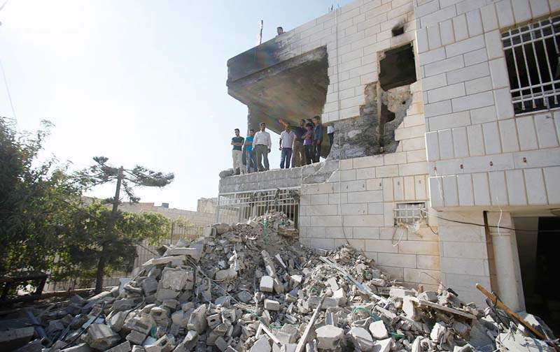 Palestinians stand in what is left of the home of Amer Abu Aisheh, one of three Palestinians identified by Israel as suspects in the killing of three Israeli teenagers, after it was demolished by the Israeli army in the West Bank city of Hebron.