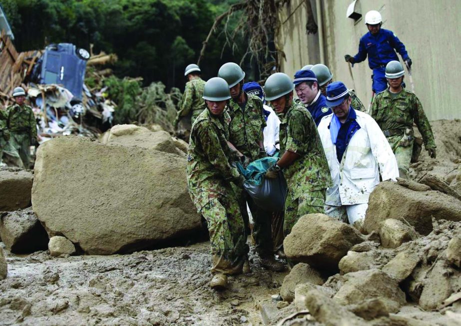 Japan Self-Defense Force (JSDF) soldiers and police officers carry the body of a victim in a plastic bag at a site where a landslide swept through a residential area at Asaminami ward in Hiroshima, western Japan.