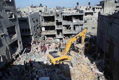 Palestinians watch as rescue workers search for victims under the rubble of a house, which witnesses said was destroyed in an Israeli air strike that killed three senior Hamas military commanders, in Rafah in the southern Gaza Strip.