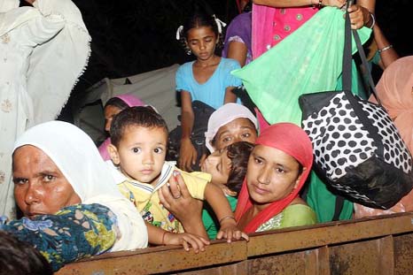 Indian border village women and children move to take shelter at a community hall in Kashmir.