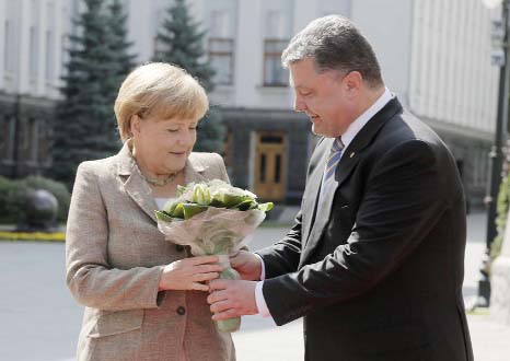 Ukraine President Petro Poroshenko, right, welcomes German chancellor Angela Merkel with a bouquet of flowers before their meeting in Kiev on Saturday