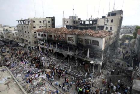 Palestinians gather around the remains of a commercial center, which witnesses said was hit by an Israeli air strike on Saturday, in Rafah in the southern Gaza Strip