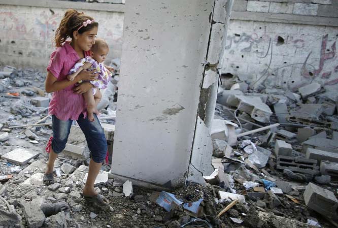 A Palestinian girl holding her baby sister walks through debris of a mosque, which was hit by an Israeli air strike, in Beit Hanoun in the northern Gaza Strip on Monday.