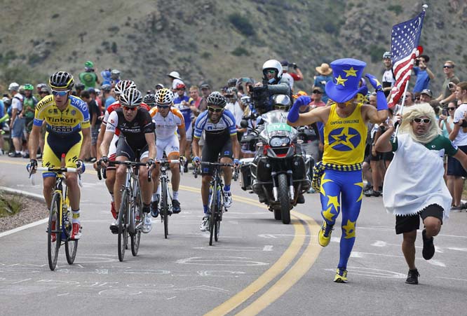 Fans run alongside cheering legendary veteran rider Jens Voight (second from left) from Germany, of team Trek Factory Racing, and Michael Rogers, far (left) from Austria, of team Tinkoff-Saxo, as they climb a mountainside above Golden, Colo., during the s