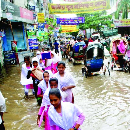 Flood water entering the different areas of the capital gradually as surrounding rivers of Dhaka are augmenting day by day. Photo shows some school-going students are crossing the knee-deep water in Shanir Akhra area on Thursday.