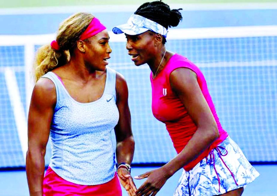 Serena Williams (left) and Venus Williams talk between points against Timea Babos and Kristina Mladenovic during a doubles match at the 2014 US Open tennis tournament in New York on Thursday.