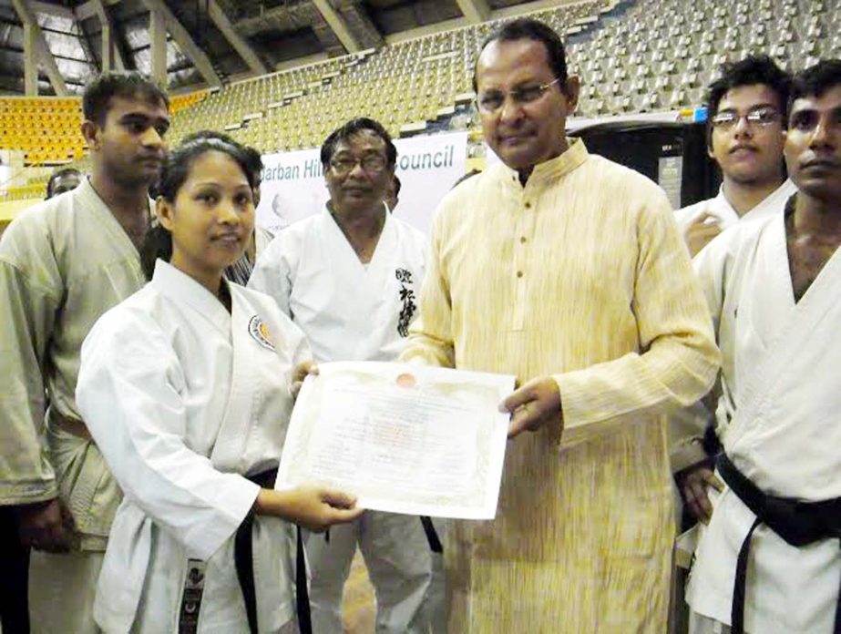 Minister for Information Hasanul Haq Inu giving away a certificate to a karateka at the Shaheed Suhrawardy Indoor Stadium in Mirpur on Saturday.