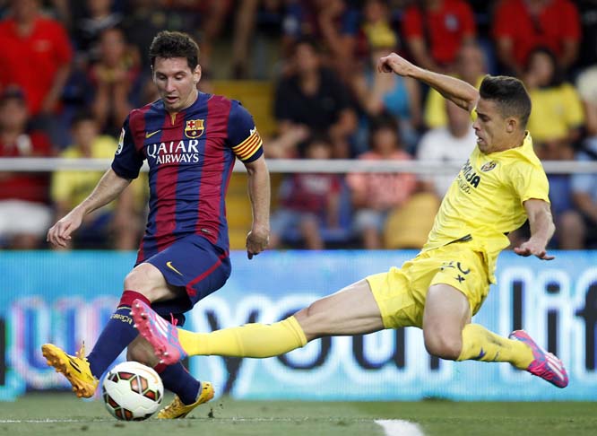 Barcelona's Lionel Messi from Argentina challenges for the ball with Villarreal's Grabiel Paulista from Brazil during a Spanish La Liga soccer match at the Madrigal stadium in Villarreal, Spain on Sunday.