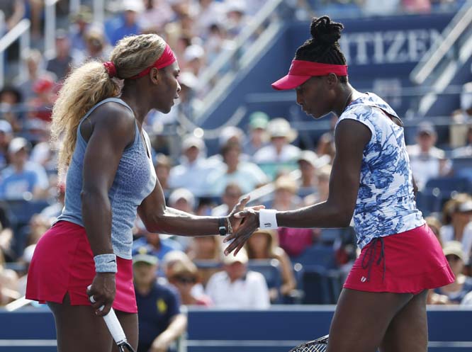 Serena (left) and Venus Williams slap hands between after a point against Garbine Muguruza and Carla Suarez Navarro of Spain during a doubles match at the 2014 US Open tennis tournament in New York on Sunday.