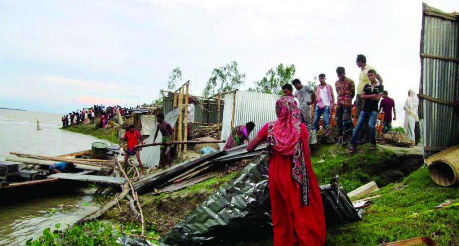 Flood affected people of Chandanbaisha Adbaria at Sariakandi moving to safer places with their household goods due to partial erosion of their village. This photo was taken on Monday.