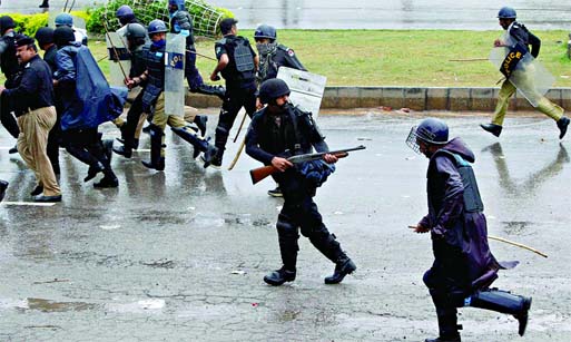 A policeman fires his weapon as he runs away with others from supporters of Tahirul Qadri during the march towards the prime minister's house in Islamabad, Sept 1, 2014. Reuters photo