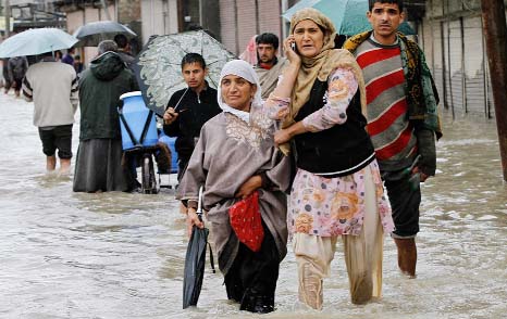 A Kashmiri woman speaks on the phone as she wades through floodwaters with others in Srinagar.