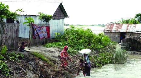 A CLF beneficiary woman providing shelter to neighbours on her raised plinth when all surrounding areas have been flooded .