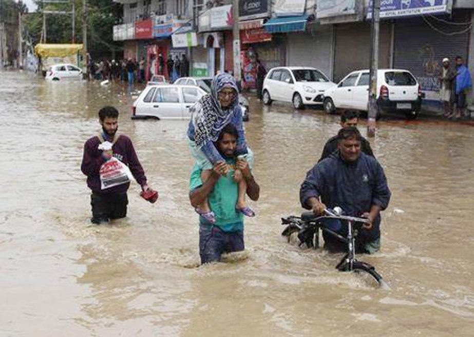 A Kashmiri man evacuates an elderly woman to a higher ground at a flooded road in Srinagar.
