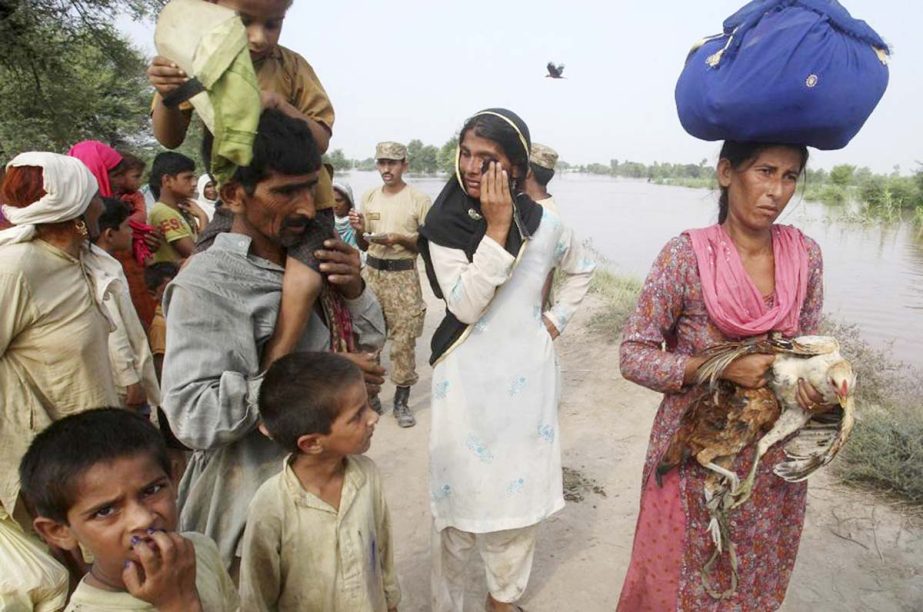 A Pakistani man carries his son and women carries a rooster are evacuated by army troops as families flee from a flooded area of Jhang district, 260 kilometers (161 miles) northwest of Lahore, Pakistan.