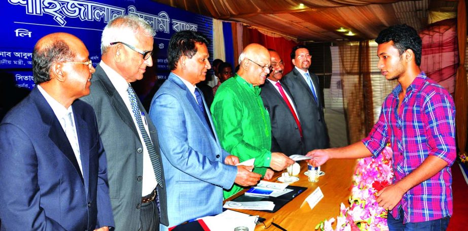 Finance Minister AMA Muhith handing over scholarship cheque to a student in a scholarship awarding ceremony organized by Shahjalal Islami Bank Limited at Officers Club in the city on Thursday. Chairman AK Azad, Managing Director Farman R Chowdhury of the