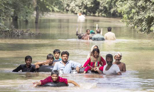 Flood victims wade through a flooded area along a road as they wait for help, in Multan, Punjab province on Sunday