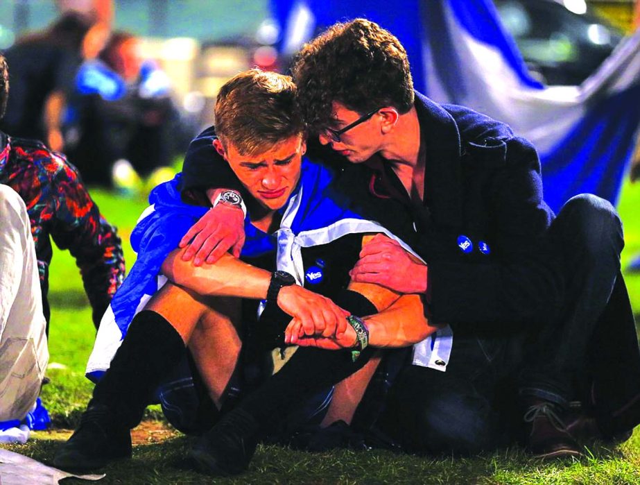 A 'Yes' supporter comforts his heartbroken friend after the result became apparent. Salmond called on Westminster to speed through devolved powers.