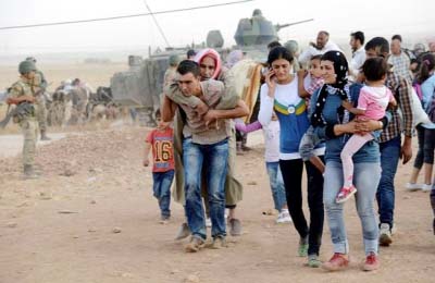 Syrian Kurds walk after crossing into Turkey at the Turkish-Syrian border, near the southeastern town of Suruc in Sanliurfa province