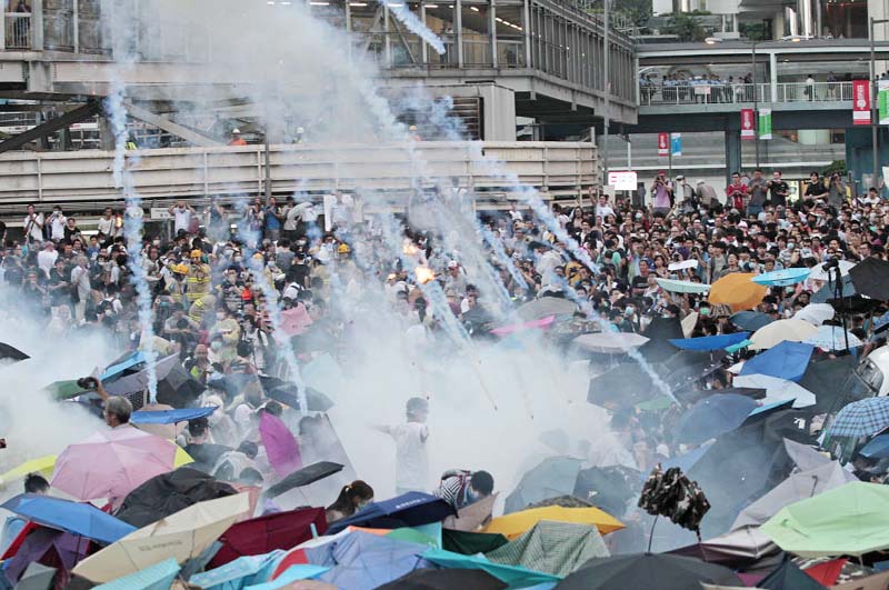 Riot police launch tear gas into the crowd as thousands of protesters surround the government headquarters in Hong Kong on Sunday.