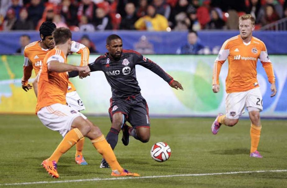 Toronto FC forward Jermaine Defoe (center) attempts to get past against Houston Dynamo players David Horst (left) Ricardo Clark and Andrew Driver (right) during second half MLS soccer action in Toronto on Wednesday.