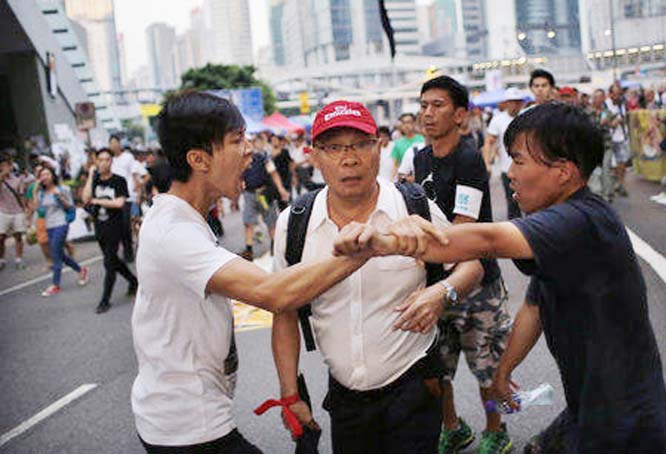 Pro-democracy protesters argue with a man as he walks away from an area blocked by protesters outside the government headquarters office in Hong Kong