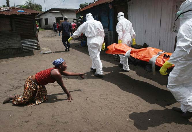 These photos, taken by photographers John Moore and Mohammed Elshamy, show the grim reality of the Ebola outbreak in Liberia, West Africa. Above, a woman crawls toward the body of her sister as an Ebola burial team takes it away for cremation