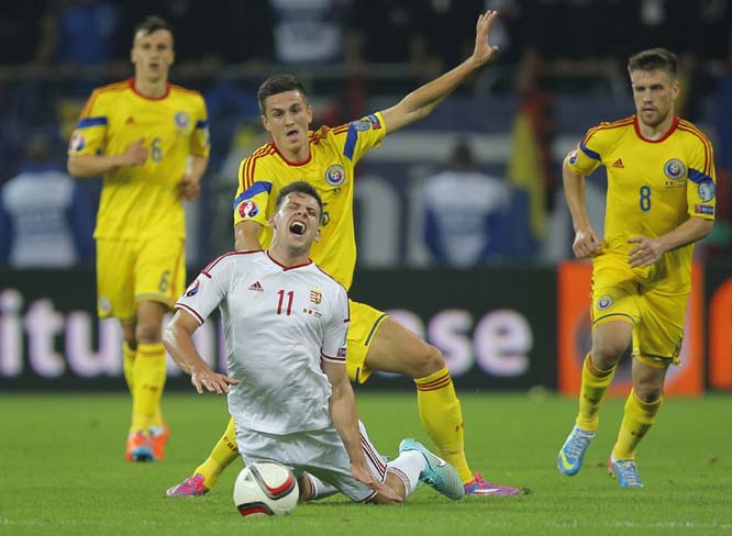 Hungary's Adam Szalai (center) falls, tackled by Romania's Florin Gardos (top center) during the Group F, Euro 2016 qualifying match between Romania and Hungary, at the National Arena stadium in Bucharest, Romania on Saturday.