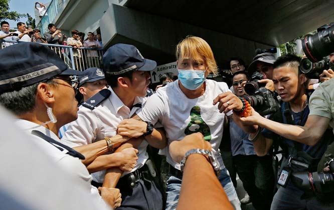 Police officers try to stop a masked-man who was removing the metal barricades that protesters have set up to block off main roads near the heart of the city's financial district, Hong Kong.