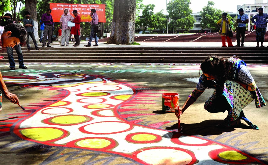 Agitated fine artists painting 'alpona' at the entrance of the Central Shaheed Minar in the city on Tuesday demanding not to bring the body of Piash Karim, Professor of BRAC University to the Shaheed Minar premises.