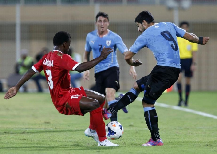 Omani player Abdullsallam al-Mukhain fights for the ball with Uruguay's Luis Suarez (R) during their friendly football match at Buraimi Sports Stadium in Oman on Monday.