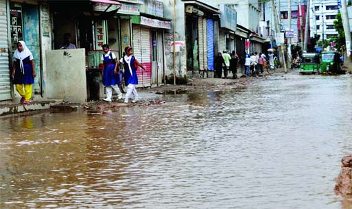 WALKING ALONG RIVER BANK ! Localâ€™s and students of Mothertek-Nandipara passing through the main road of the area that remained inundated following recent rains. This photo was taken on Thursday.