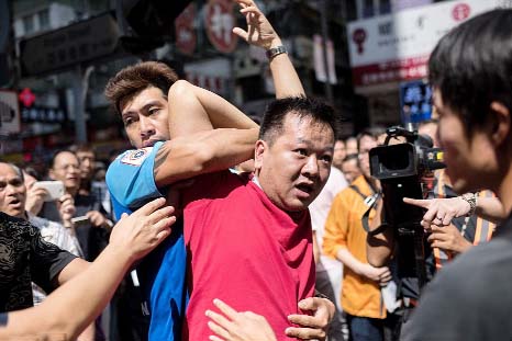 A man is restrained after he confronted people standing next to a pro-democracy protest barricade in the district of Mong Kok.