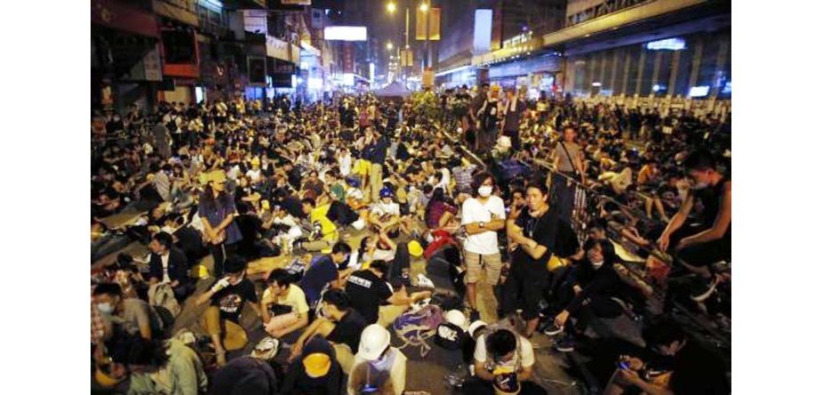 Pro-democracy protesters sit on a street as they block an area of the Mongkok shopping district of Hong Kong on Monday.