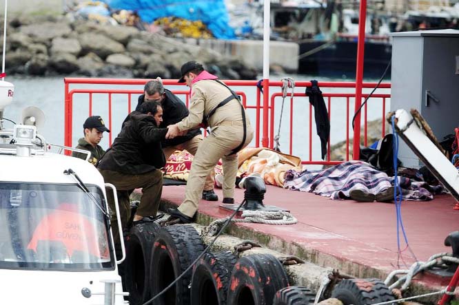 Turkish officials assist a survivor while the bodies of illegal migrants lie on the ground in Istanbul, on Monday.