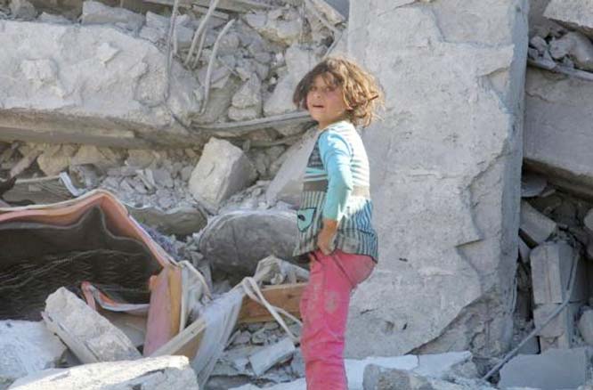 A girl inspects damage of collapsed buildings after US-led air strike on Kafar Joum village in West Aleppo.