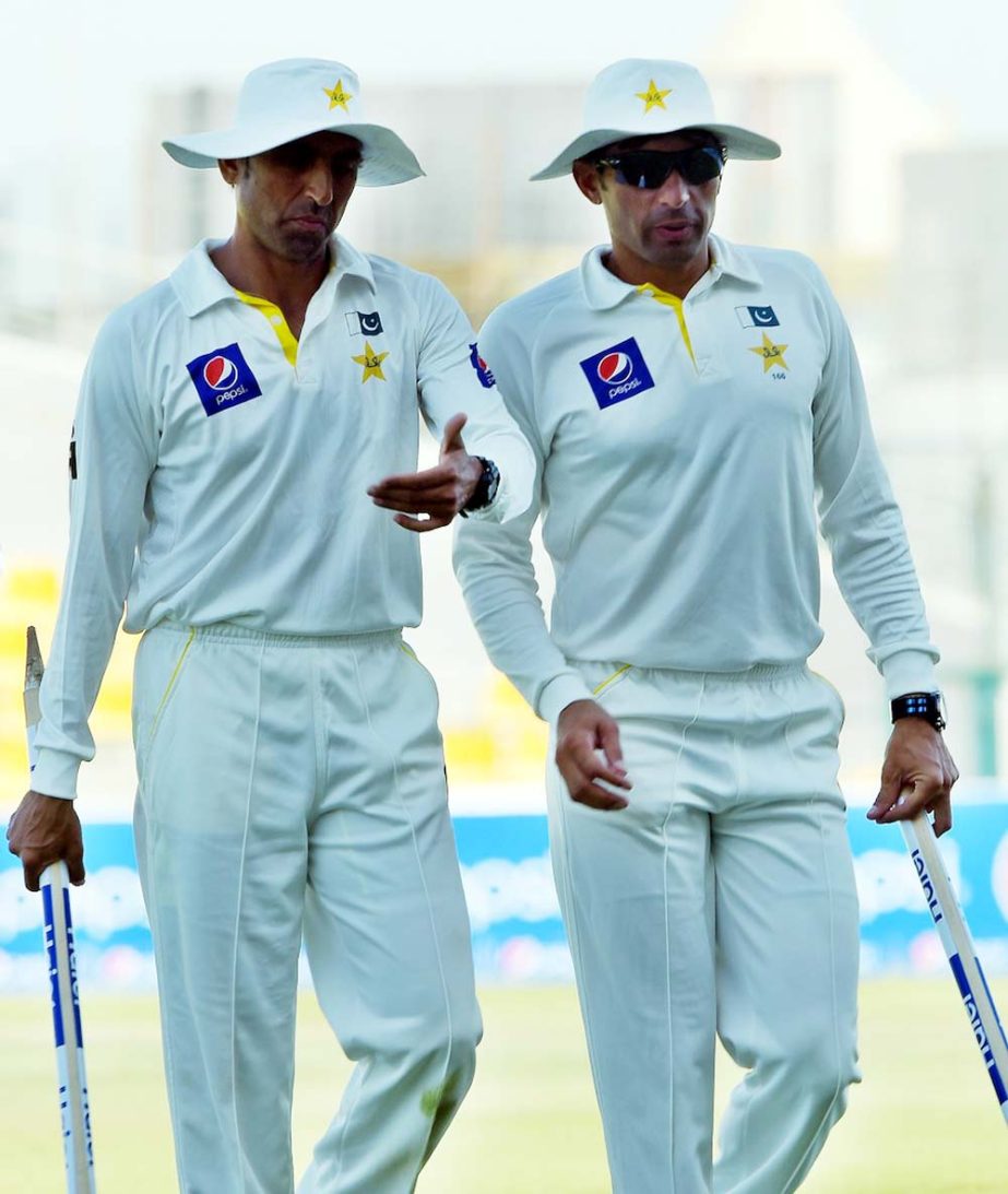 Pakistani cricket captain Misbah-ul Haq (R) and teammate Younis Khan carry the wickets after beating New Zealand at the end of the fifth and final day of the first Test match between Pakistan and New Zealand at the Zayed International Cricket Stadium in A