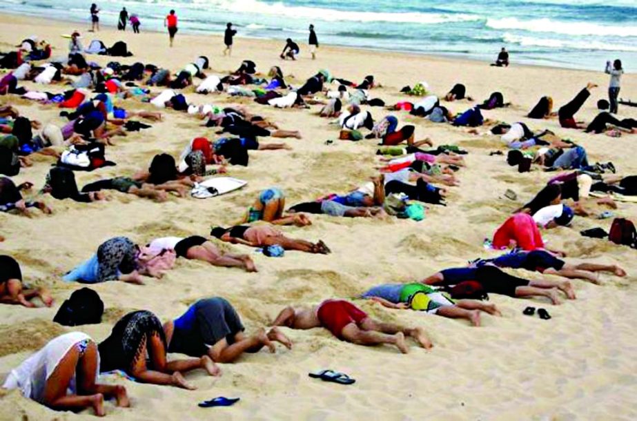 A group of around 400 demonstrators participate in a protest by burying their heads in the sand at Sydney's Bondi Beach.