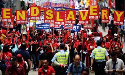 Migrant workers holding placards in Britain saying â€˜End slaveryâ€™ during a protest demonstration.