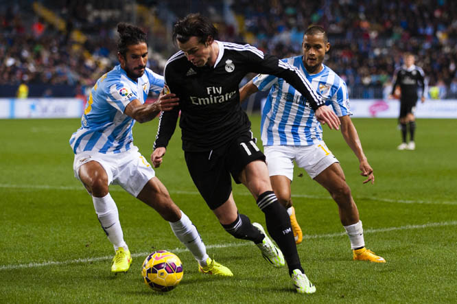 Real Madrid's Gareth Bale from Wales (center) duels for the ball against Marcos Alberto Angeleri from Argentina (left) and Roberto Jose Rosales from Venezuela (right) during the Spanish La Liga soccer match between Malaga and Real Madrid at La Rosaleda S
